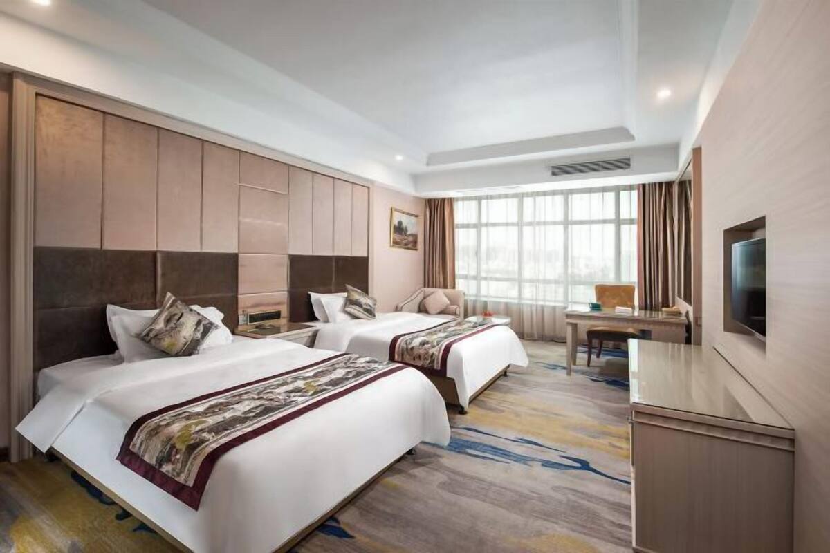 Une chambre d’hôtel avec deux lits, un bureau et une télévision.