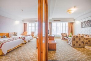 Habitació d'hotel amb un llit gran, un sofà, un armari de fusta i un escriptori.