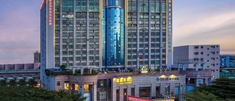 A multi-story hotel with a prominent central tower, multiple balconies, and a ground-level commercial area with signage.