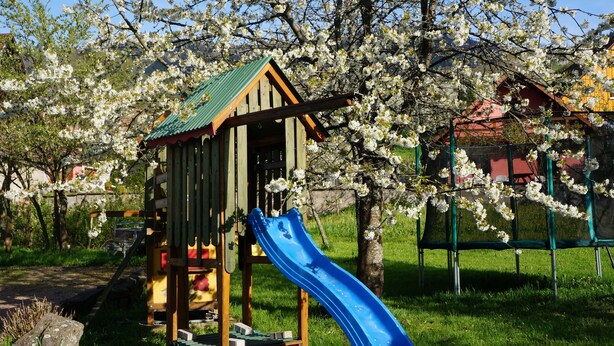 Une aire de jeux avec un toboggan et une cabane en bois.