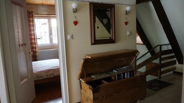 Une chambre à coucher avec un lit, une commode en bois, un miroir et un escalier.