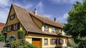 Il s’agit d’un bâtiment traditionnel à deux étages, doté d’un toit à forte pente, de volets en bois et d’une enseigne indiquant qu’il s’agit d’une maison d’hôtes.