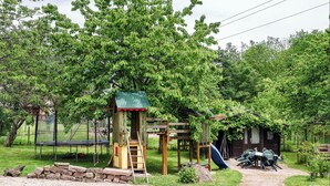 Une aire de jeux avec des balançoires, un toboggan et un trampoline.