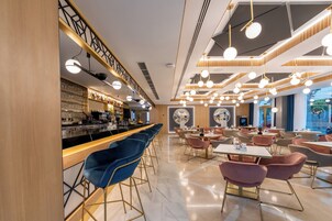 A modern bar area with a long counter, blue bar stools, and a variety of seating options including tables and chairs in the dining area.