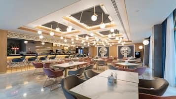 Een modern restaurant met een bar, diverse zitmogelijkheden en een uniek plafondontwerp.