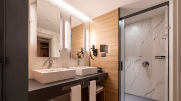 Un baño moderno con dos lavamanos, un espejo grande y una cabina de ducha de vidrio.