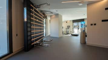 Un gimnasio moderno con equipo de ejercicio, dispensador de agua y un amplio ventanal.