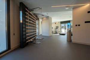 Un gimnasio moderno con equipo de ejercicio, dispensador de agua y un amplio ventanal.