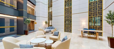 A spacious lobby with a seating area, a staircase, and a decorative wall.