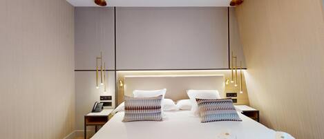 A modern hotel room with a large bed, bedside tables, a phone, and a robe on the bed.