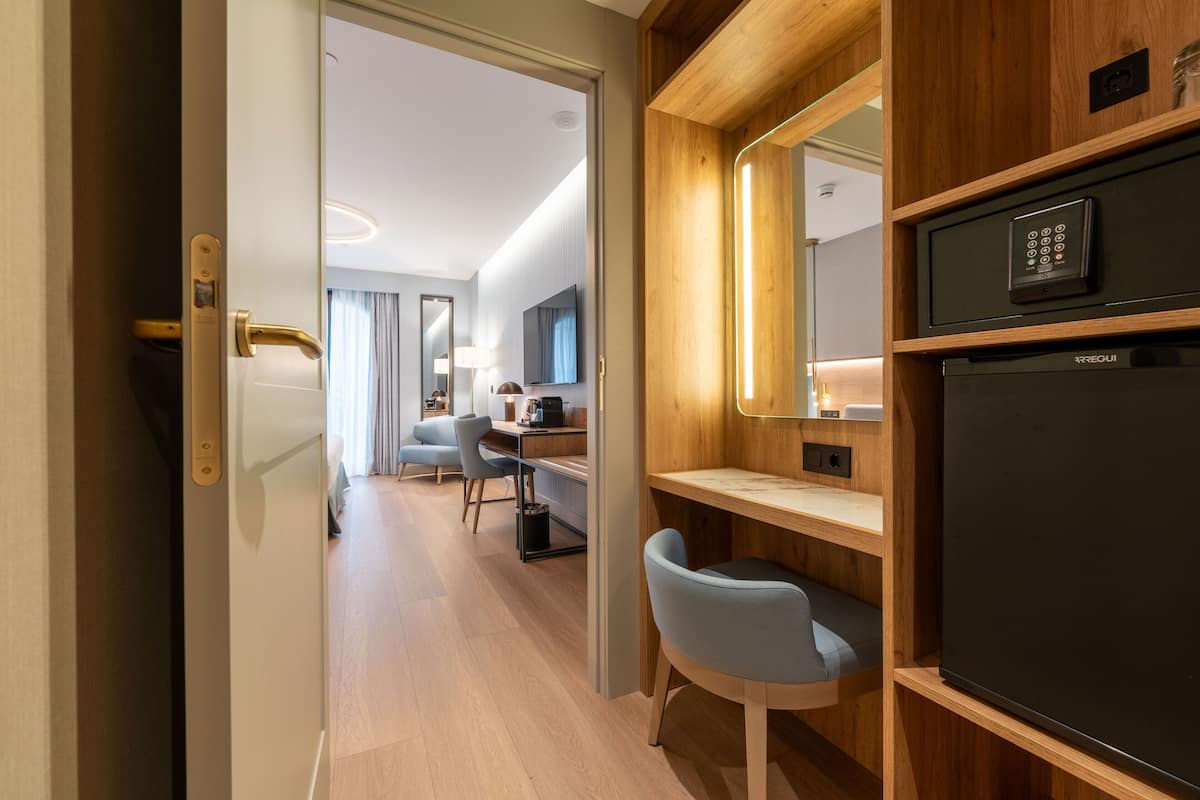 Een moderne hotelkamer met een houten bureau, een stoel, een televisie en een minibar.