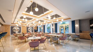 Een ruim restaurant met modern decor, meerdere eetgedeeltes en een centrale zithoek.