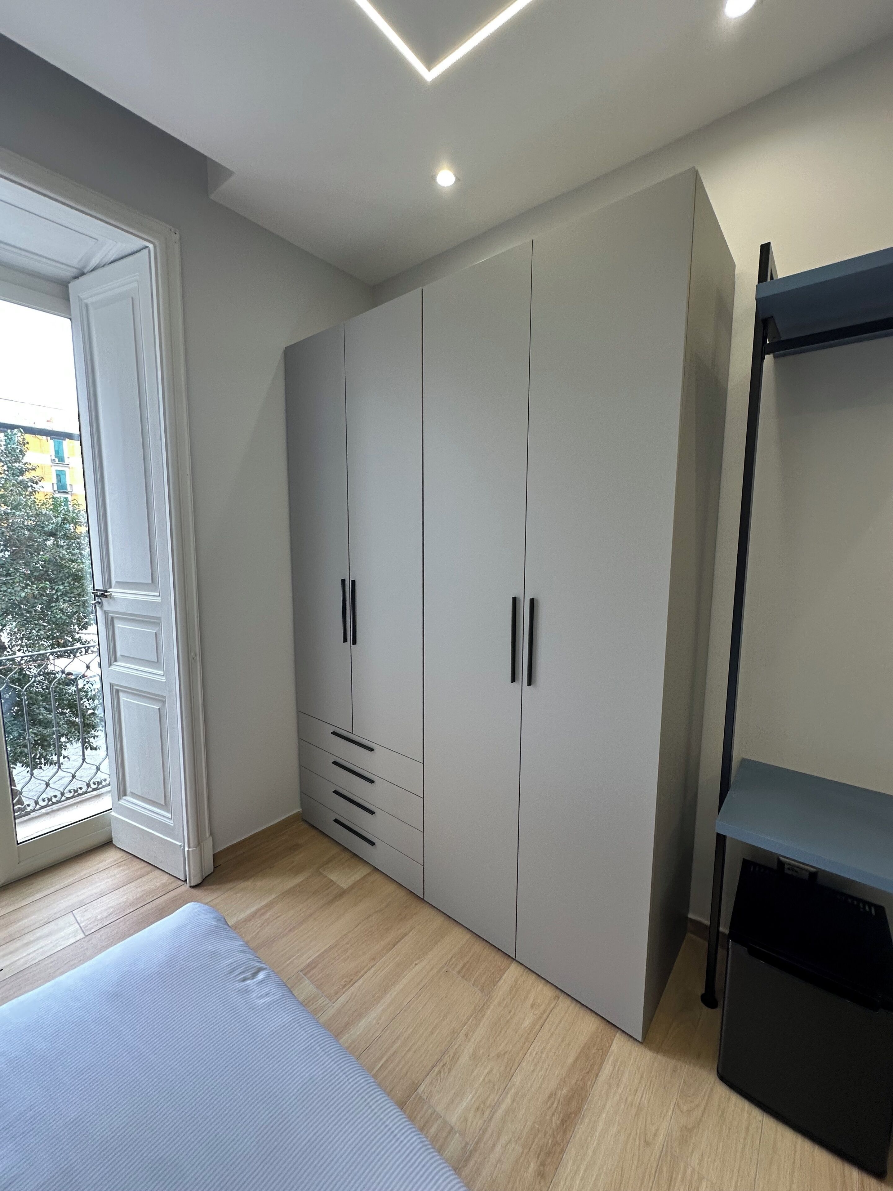 A bedroom with a large wardrobe, a bed, and a balcony.