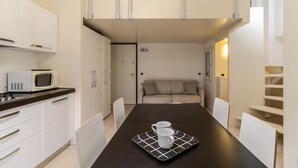 Une cuisine compacte avec des meubles blancs, un four à micro-ondes et une table à manger agrémentée de deux tasses blanches.