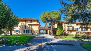 A residential building with a central entrance, multiple balconies, and a well-maintained lawn. - Sporting 1 64 by Wonderful Italy (Sirmione)
