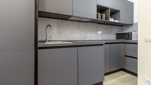 A modern kitchen with grey cabinets, a stainless steel sink, and a microwave. - Sporting 1 64 by Wonderful Italy (Sirmione)