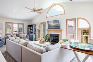 A spacious living room with a sectional sofa, a fireplace, a television, and large windows. - Isle of Dreams: Almost Oceanfront 4 Bedrooms 4 Baths Atlantic Beach (Atlantic Beach)
