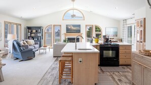 A spacious living room with a fireplace, a kitchen with a large island, and a dining area.
