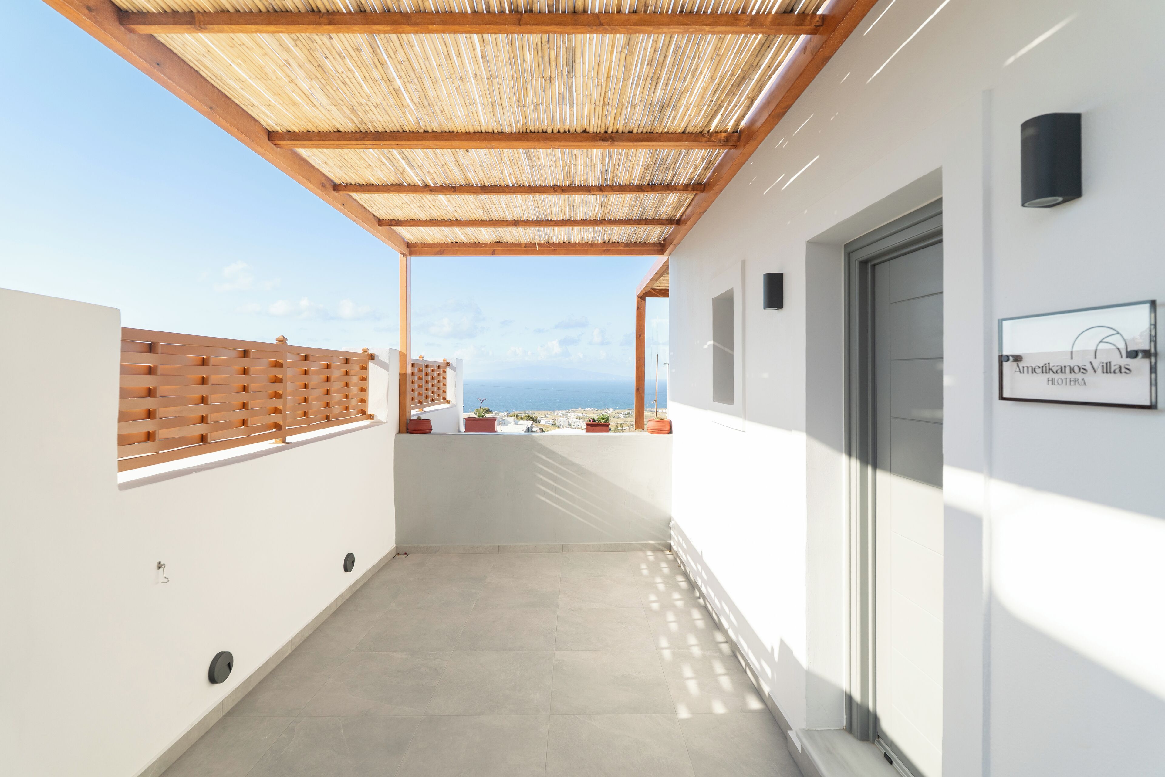 En inglasad balkong med utsikt över havet, ett trästaket och en skylt för Amerikanos Villas.