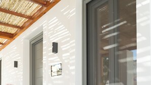 Een modern gebouw met een witte gevel, een houten plafond en een raam met een metalen zonwering.