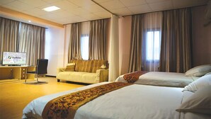 Una habitación de hotel con cama, sofá, escritorio y ordenador, además de cortinas.