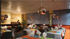Un restaurante con varias mesas dispuestas para comer, con manteles coloridos y servilletas blancas.