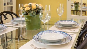 A dining table set with blue and white plates, a green vase with flowers, and wine glasses. - Comfort 4 minutes from Leblon Beach | AP801 (Rio de Janeiro)