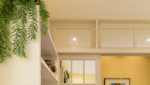 A room with a white door, a bookshelf with books and decorative items, a framed picture on the wall, and a tiled floor. - Comfort 4 minutes from Leblon Beach | AP801 (Rio de Janeiro)