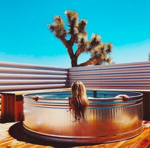 A person relaxing in a hot tub with a desert tree in the background. - Desert Bliss Joshua Tree -Cowboy Pool & Tub. close to Pappy & Harriet's & Park. (Joshua Tree)