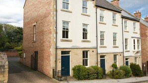 A row of terraced houses with a brick facade, white-painted exterior, and multiple windows. - Churchside (Alnwick)