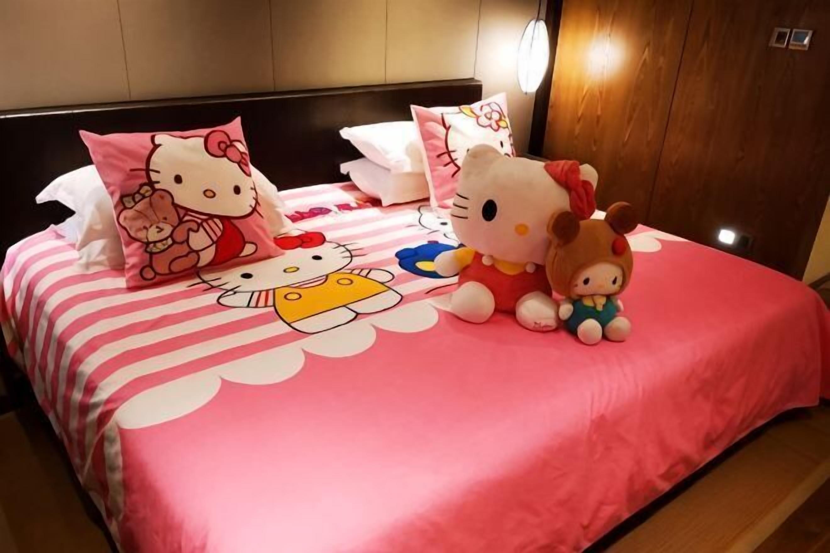 A bed with pink bedding and Hello Kitty-themed pillows.