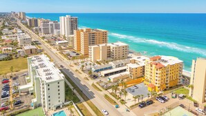 A coastal cityscape with high-rise buildings, a beachfront, and a parking area. - Oceanfront | No-drive Beach | Sea Fern #303 (Daytona Beach Shores)