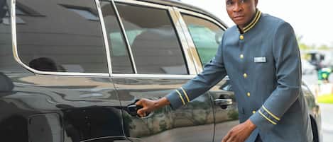 A man in a uniform opening a car door.