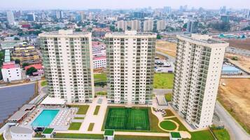 A high-rise residential building complex with multiple apartment buildings, a swimming pool, and a tennis court.
