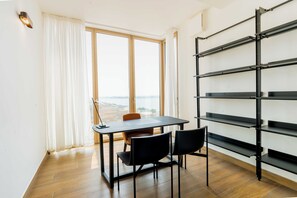 Una habitación con un ventanal grande, una mesa con sillas y una estantería metálica negra.