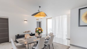 Un comedor moderno con una mesa redonda, seis sillas, un jarrón de flores y una lámpara colgante.
