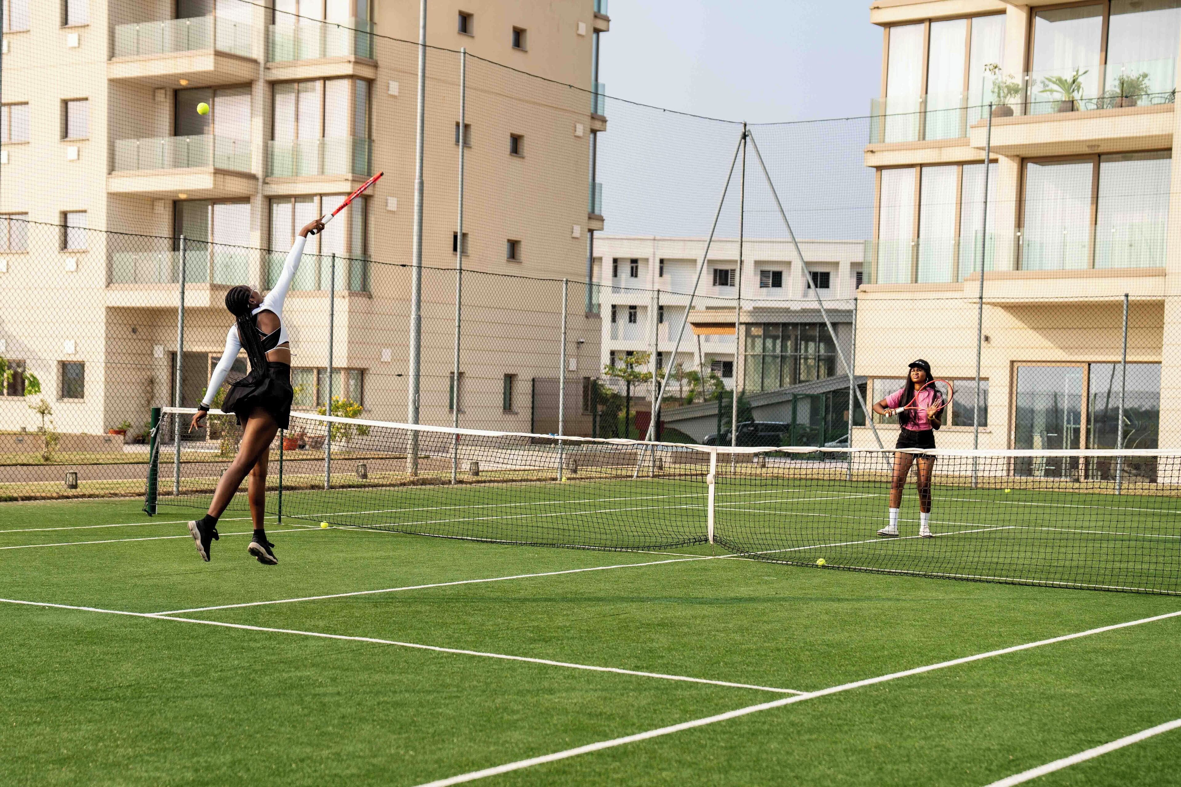 A tennis court with a net in the middle, surrounded by a chain-link fence.