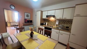 Uma cozinha compacta com uma mesa de jantar posta para quatro pessoas, geladeira e micro-ondas.