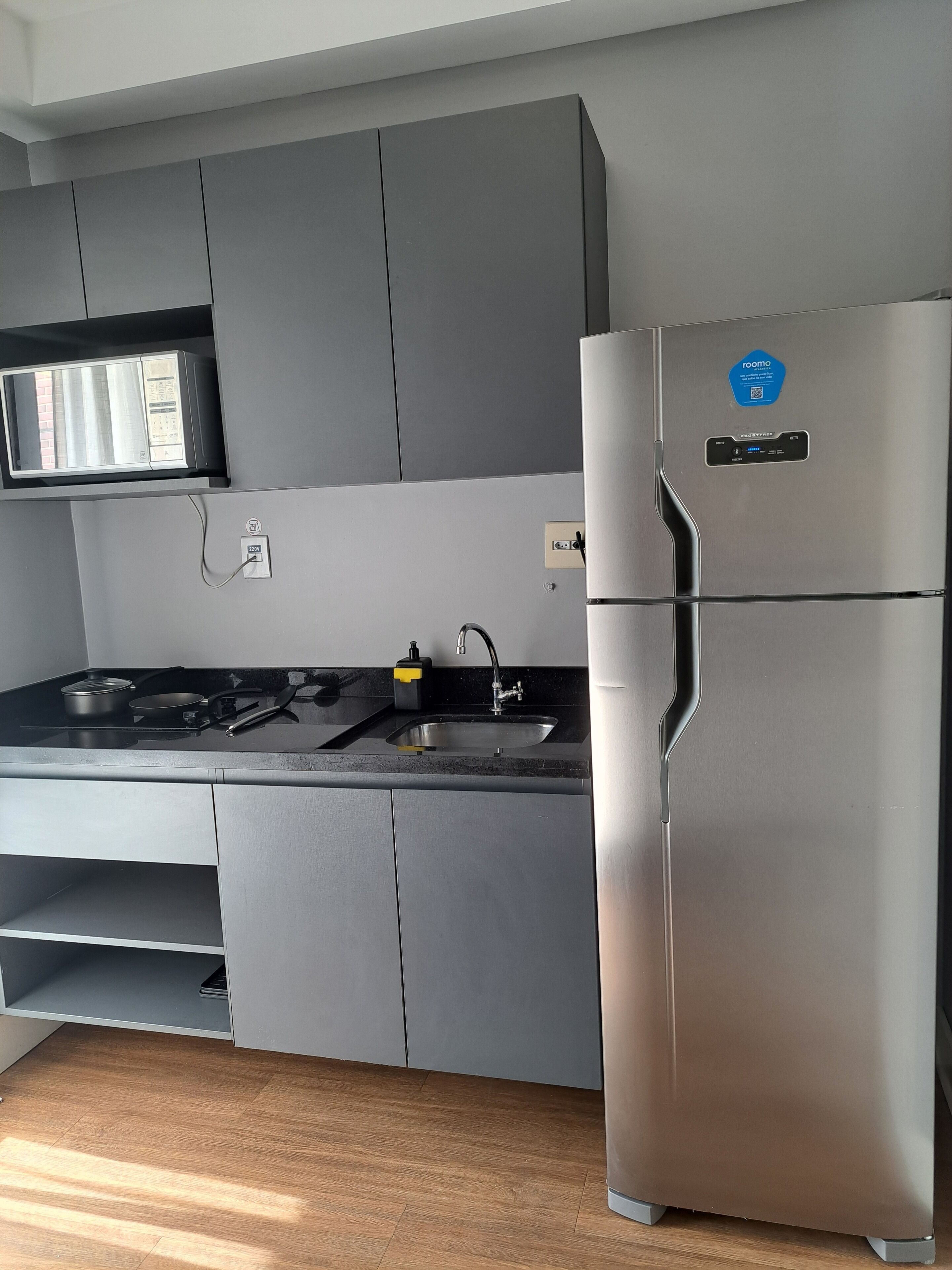 Eine moderne Küche mit grauen Schränken, einem Edelstahlkühlschrank, einer eingebauten Mikrowelle und einem Gasherd.