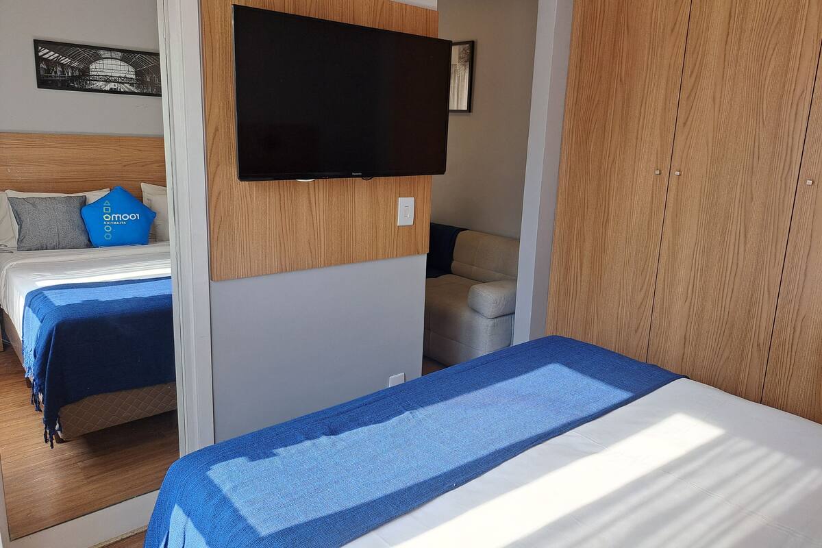 Hotellihuone, jossa on kaksi sänkyä, seinälle asennettu televisio ja vaatekaappi.