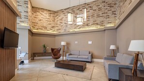 Un salon moderne avec un téléviseur à écran plat, un fauteuil en cuir marron, un canapé gris et une table basse.