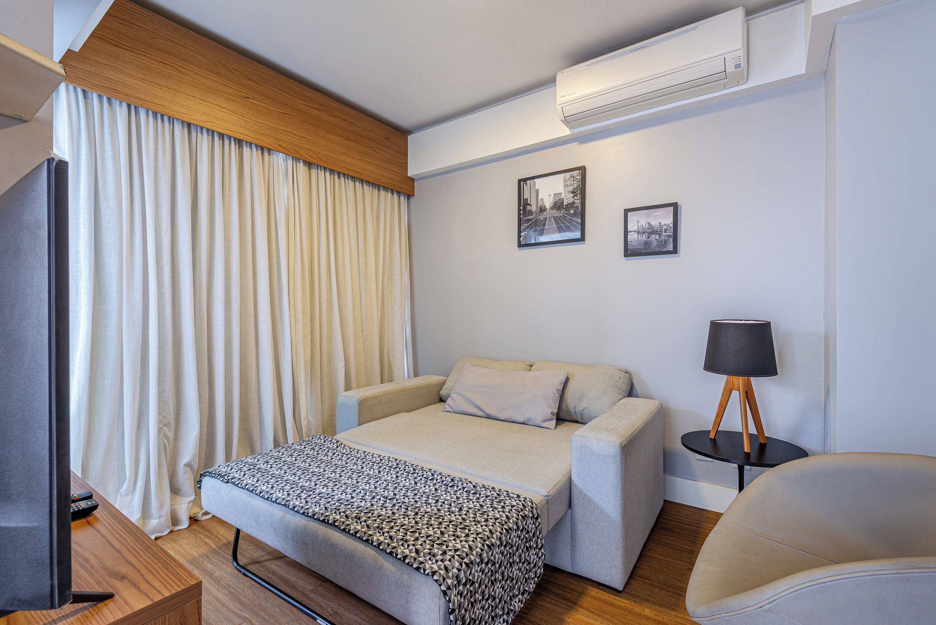 Ein Schlafzimmer mit Bett, Fernseher, Lampe und Stuhl.