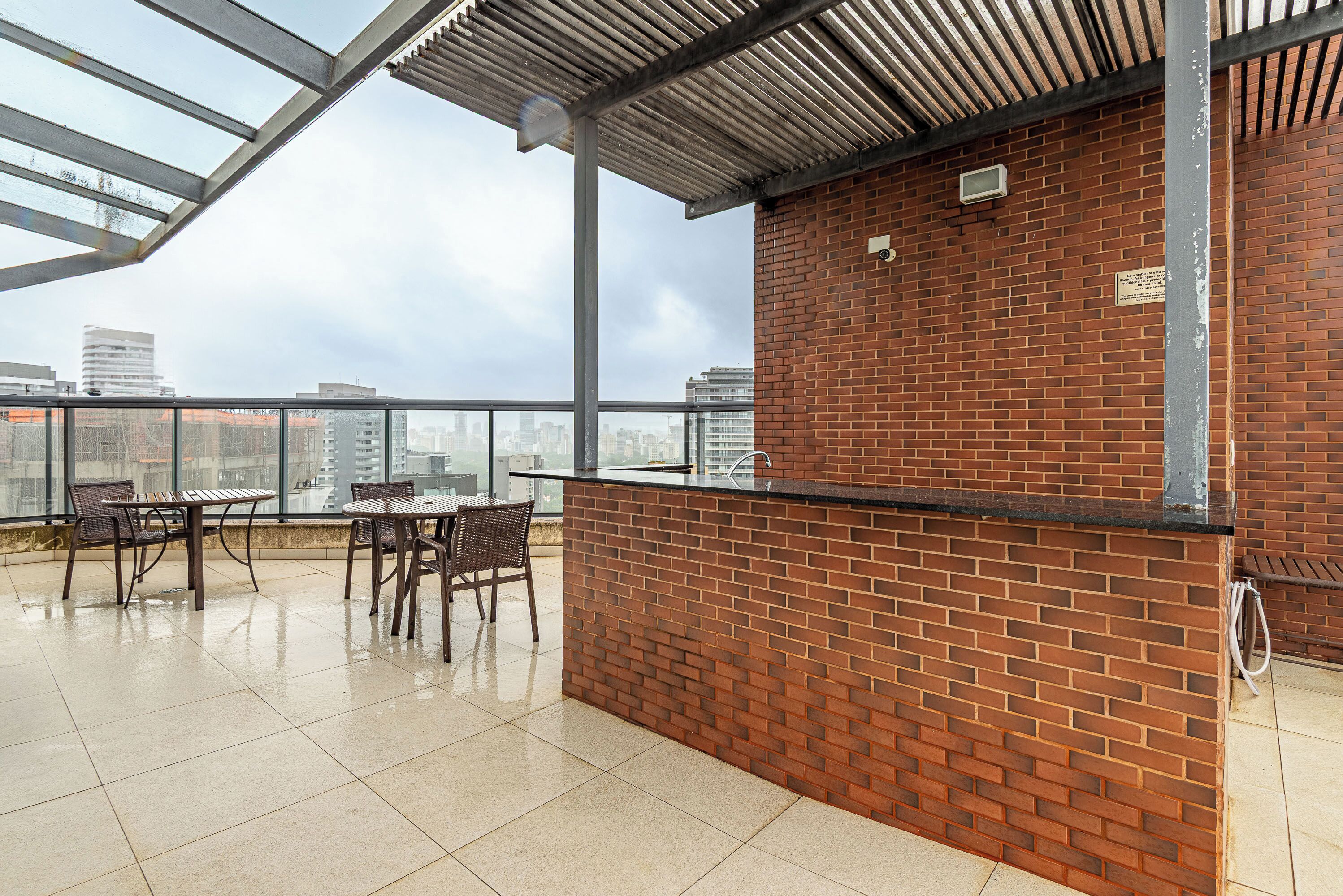 A rooftop terrace with a brick wall, metal roof, and glass railings.