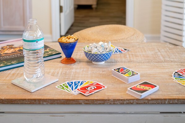 A wooden table with a water bottle, a bowl of snacks, and UNO cards.