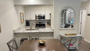 A modern kitchen with white cabinets, a stainless steel microwave, and a granite countertop. - Charming 2 bedroom townhome in Seagrove steps to the beach! (Santa Rosa Beach)