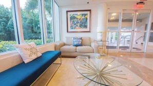 Eine moderne Lobby mit einem blauen Sofa, einem Glastisch und einem Gemälde an der Wand.