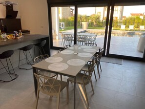 Un comedor con una mesa dispuesta para seis personas, sillas y una encimera de cocina con diversos objetos.