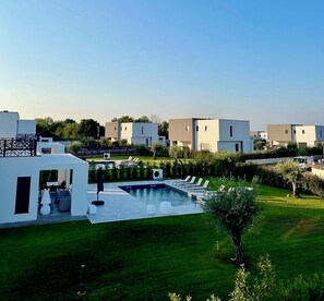 Una zona residencial moderna con piscina, sillas de descanso y un césped bien cuidado.
