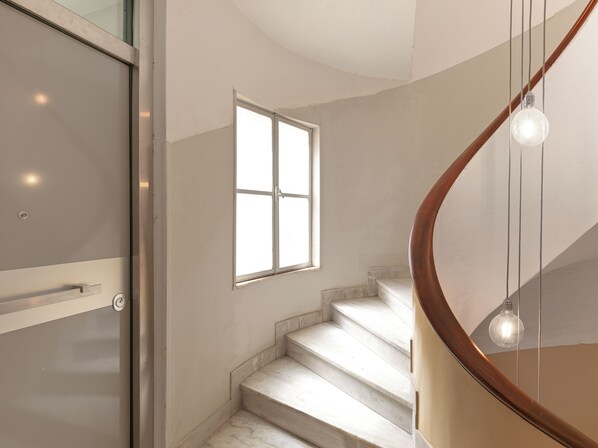 A modern staircase with a wooden handrail and a glass balustrade.