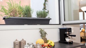 A kitchen counter with a coffee maker, tea set, fruit, and potted plants.